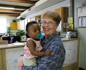 AN URGENT NEED Sister Peg Spindler holds one of her youngest clients, as another client shops.
