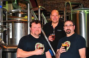 BEER FOR BLUE COLLARS Bulldog Brewing Co. in Whiting produces 27 different labels of beer. Pictured are the three partners—brewmaster Kevin Clark, Jeff Kochis and Bob Faust—in front of the seven-barrel brewing system that is visible from the “front of the house” and 119th Street.